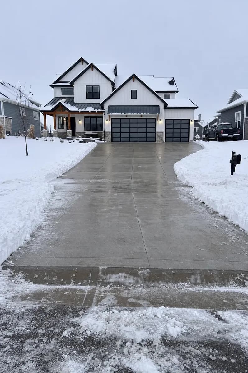 A concrete driveway cleared in front of a farmhouse